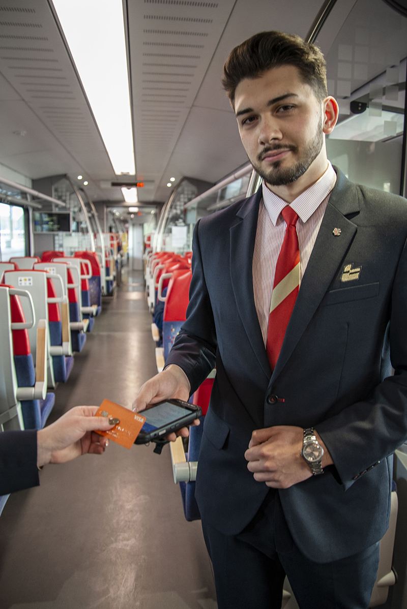 Konduktor w pociągu przyjmuje płatność kartą płatniczą urządzeniem do wydawania biletu. 