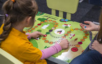 Powiększ zdjęcie: Zdjęcie przedstawia dzieci grające w grę planszową ŁKA. 