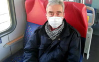 Powiększ zdjęcie: Na zdjęciu pasażer ma założona maseczkę na twarzy.