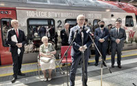 Powiększ zdjęcie: Prezes Janusz Malinowski przemawia na tle pociągu.