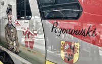 Powiększ zdjęcie: Widok czoła pociągu, na nim rysunkowa postać Pogonowskiego.