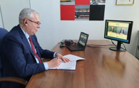 Powiększ zdjęcie: Prezes Janusz Malinowski podpisuje porozumienie, na monitorze widoczny jest prezes PKP Energetyka.