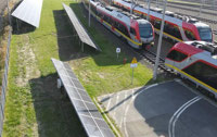 Powiększ zdjęcie: Widok pod kątem z góry na panele na zapleczu, obok torowisko z pociągami ŁKA.