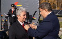 Powiększ zdjęcie: Marszałek WŁ Grzegorz Schreiber przypina do piersi odznakę "Zasłużony dla kolejnictwa" uhonorowanej osobie.