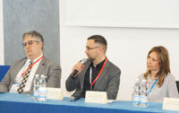 Powiększ zdjęcie: Na zdjęciu trzy osoby uczestniczące w konferencji, Zabiera głos Dominik Witkowski.