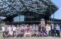 Powiększ zdjęcie: Zdjęcie przedstawia organizatorów i uczestników Wystawy Makiet Kolejowych na tle Dworca Łódź Fabryczna.