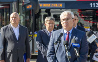 Powiększ zdjęcie: Prezes Janusz Malinowski przemawia na konferencji, w tle autobusy. 