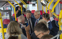 Powiększ zdjęcie: Na zdjęciu Marszałek Województwa Łódzkiego Grzegorz Schreiber oraz prezes Janusz Malinowski zwiedzają wnętrze autobusu, w otoczeniu fotoreporterzy.
