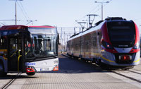 Powiększ zdjęcie: Zdjęcie przedstawia autobus i pociąg stojące obok siebie na zapleczu technicznym.