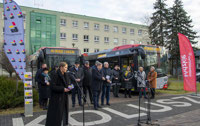 Powiększ zdjęcie: Na zdjęciu uczestnicy konferencji na tle autobusów oraz urzędu miejskiego w Koluszkach.